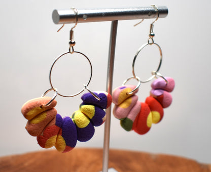 Handcrafted polymer clay bead hoop earrings in bold mismatched colours including purple, yellow, orange, pink and red on a silver hoop