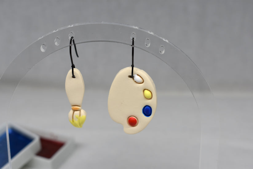 Handmade polymer clay mismatched paintbrush and artist palette earrings with yellow bristle tip on matte black hooks